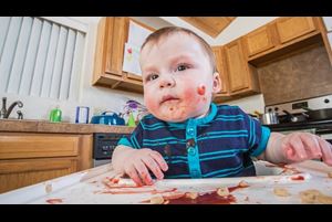 A messy child eats breakfast in the kitchen