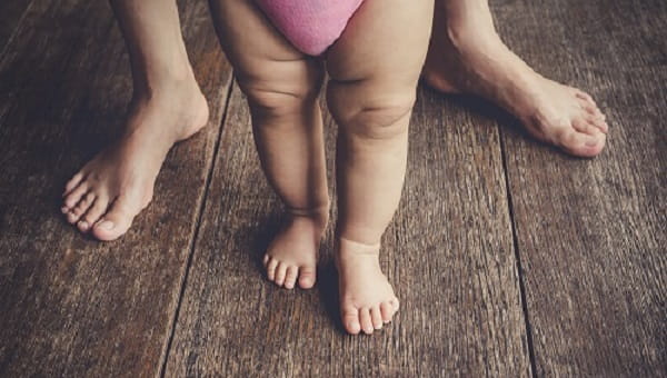 happy baby learning to walk with mother help