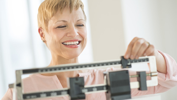 A woman weighs herself on a scale.