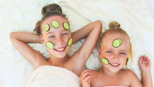 Two girls are enjoying a spa day with cucumber slices on their faces.