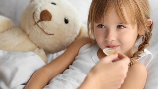 A mom gives a dose of medicine to her daughter