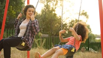babysitter and child swinging outside