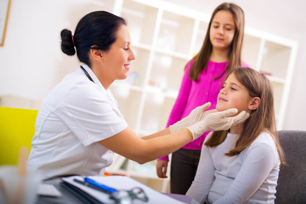 female doctor examining two young female patients