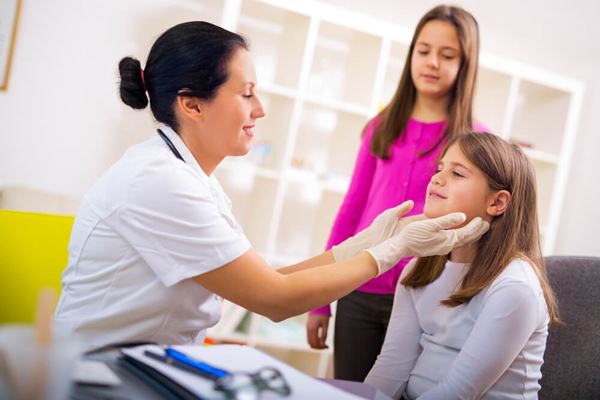 female doctor examining two young female patients