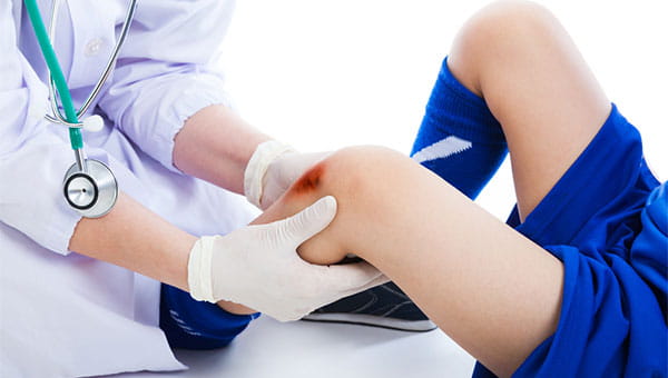 A doctor treats a wound on the knee of a young athlete
