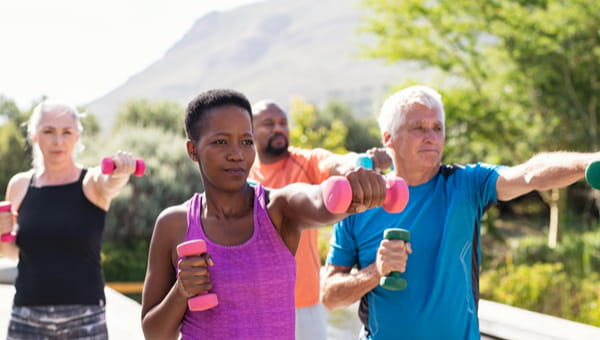Happy seniors and mature couples exercising with dumbbells. Healthy multiethnic people exercising using dumbbells outdoor