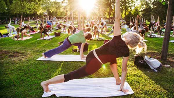 group of people outside doing yoga stretches