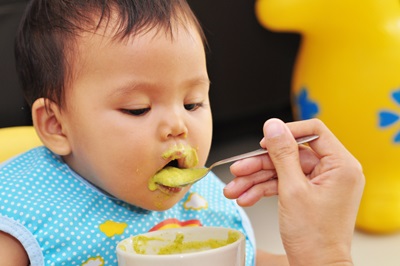 A dad is feeding his baby solid food.