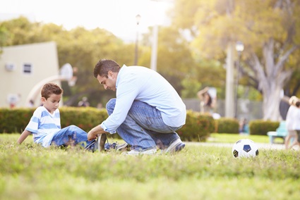 A father helps his son who injured his leg playing soccer.