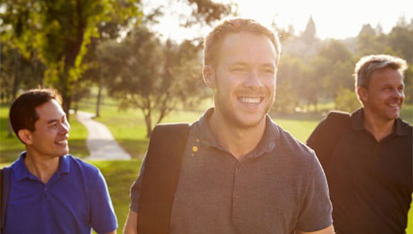 Three men smiling on a golf course.
