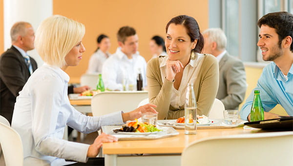 three people sitting at a lunch table talking