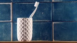A toothbrush sitting in a cup in the bathroom