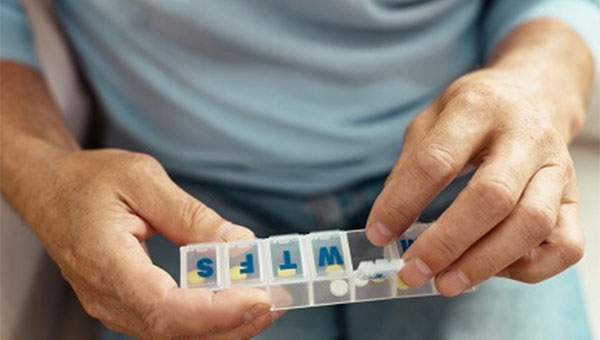 A person acquiring their medication from a daily pillbox