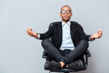 A person seated cross-legged in an office chair meditating