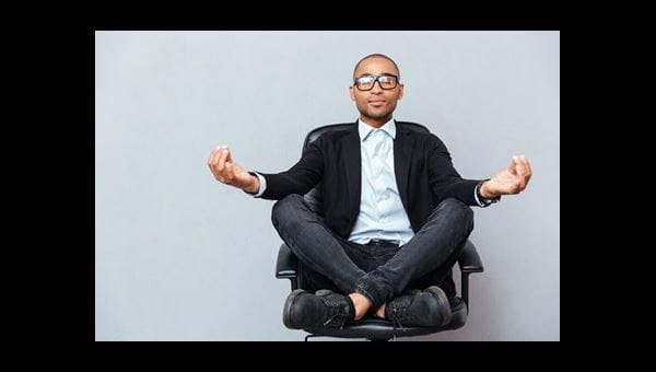 A person seated cross-legged in an office chair meditating