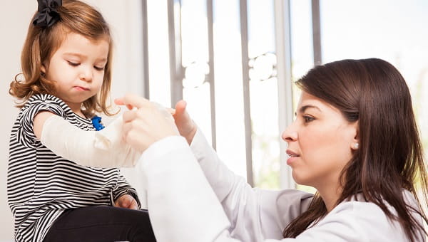 A doctor is checking a girl's broken arm.