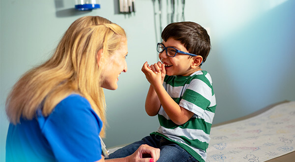 image of a doctor making a smiling boy who is sitting on an exam table