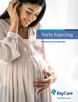Cover image of the maternity Guide showing a pregnant woman glancing at her baby bump