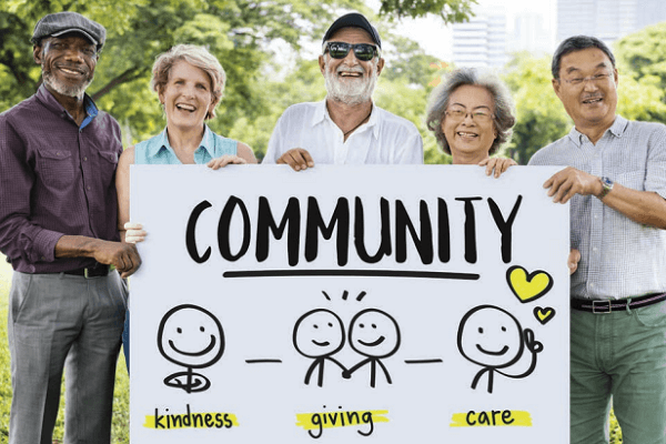 A group of men and women who are holding a sign that says "Community: Kindness, Giving and Care."