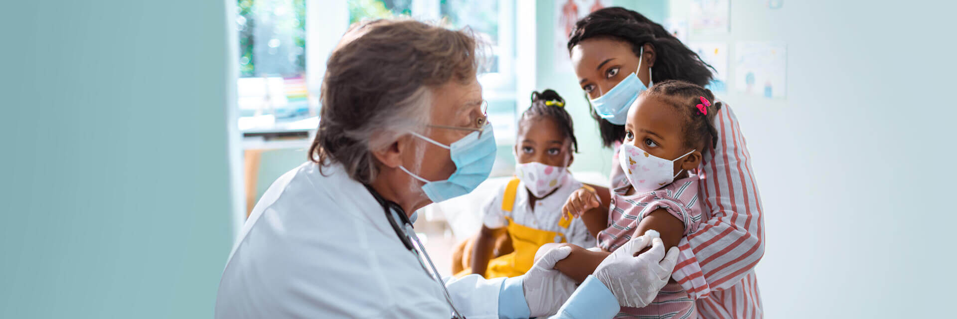 Male physician taking care of a mother and two children in a doctors office