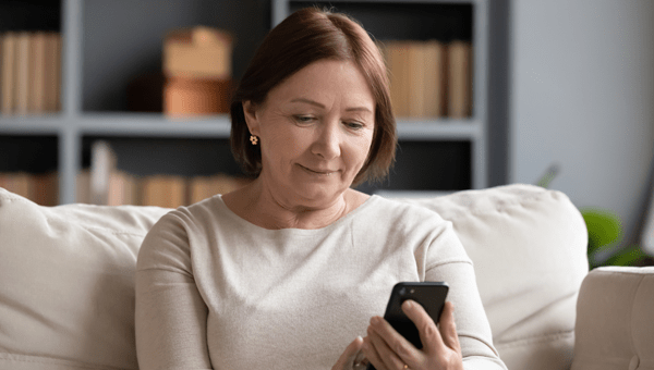 a woman sitting on her couch looking at smart phone