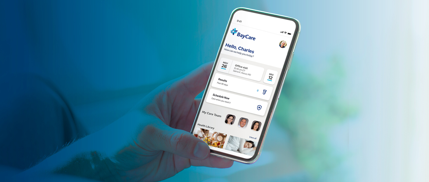 Image with blue overlay of a hand holding a mobile phone, displaying the BayCare App mobile experience.