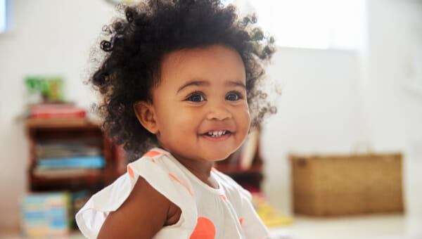 a little girl with curly hair smiling in her room