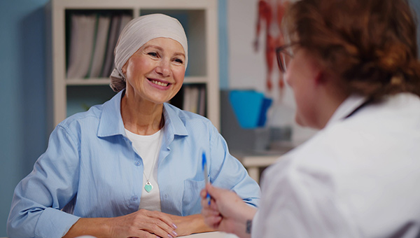 A female cancer patient converses with a doctor in a clinical setting.