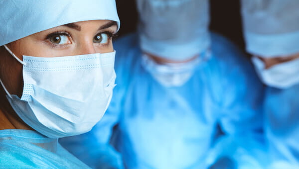 Group of surgeons wearing safety masks performing operation