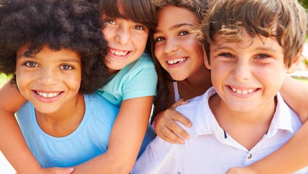 A group of boys and girls are smiling while playing outside.