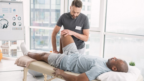 A physical therapist is providing treatment to a man's knee.