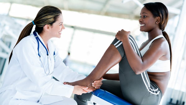 physician holding a sitting patients foot