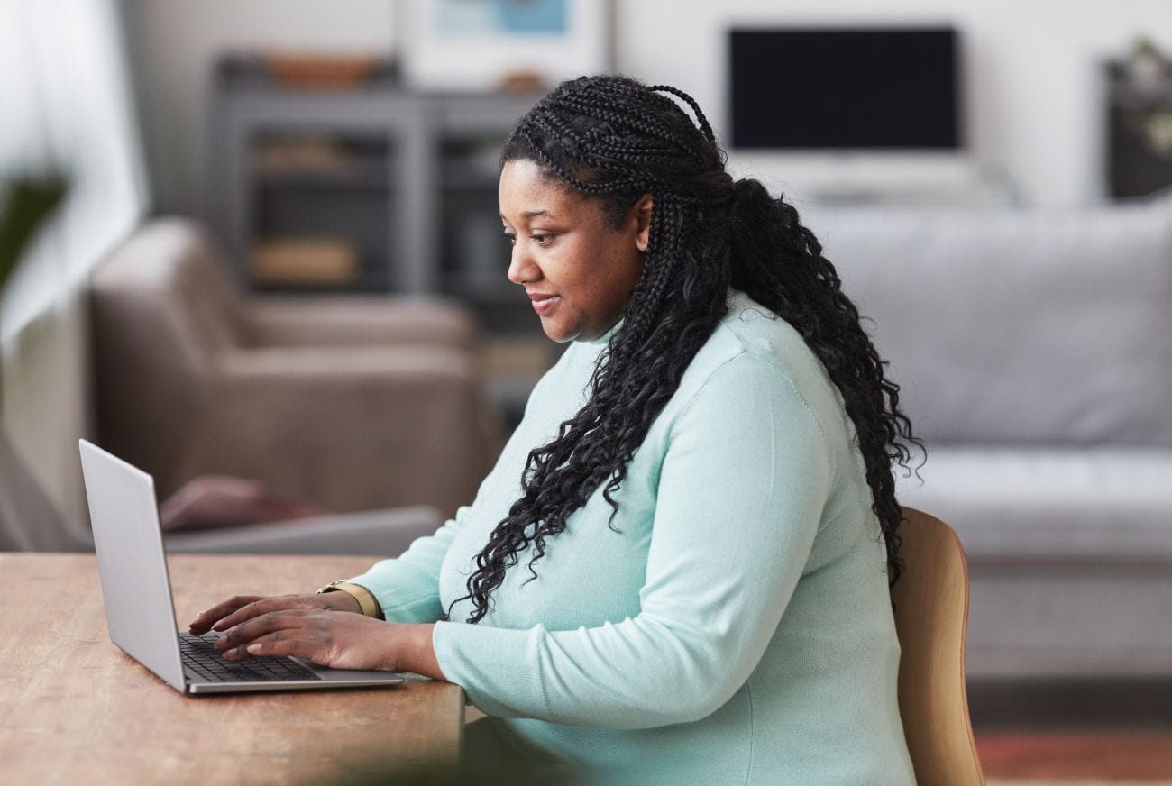 Start your weight loss journey with BayCare today. Side view portrait of curvy African American woman using laptop at desk