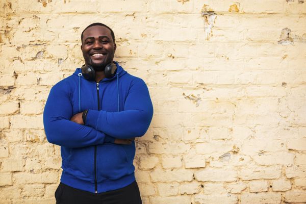 A man with headphones crossing his arms and smiling