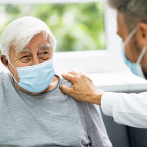 Male physician encouraging older male patient with a hand on his shoulder
