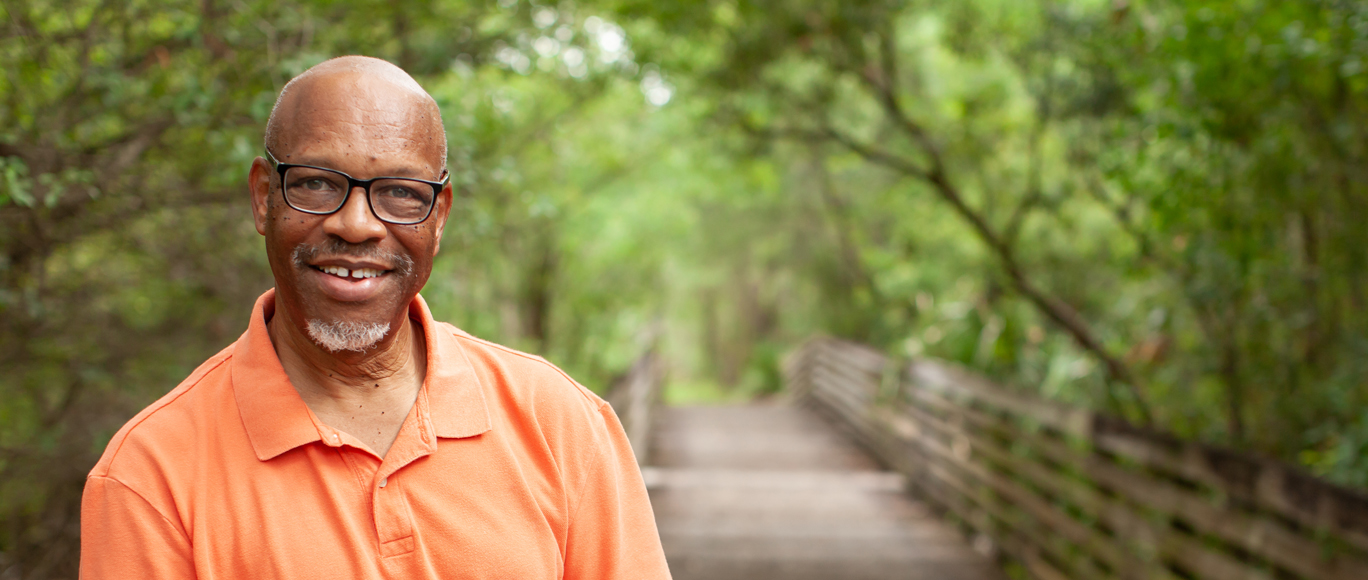 BayCare Plus Member David C, an older man with glasses, wearing an orange shirt.