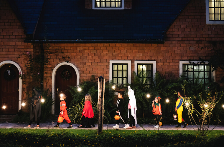 Children trick-or treating walking on lighted sidewalk