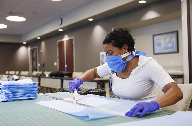 Team member cutting materials for face masks