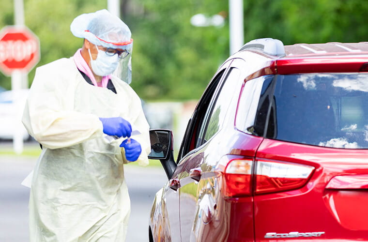 Medical professional standing beside a card at a covid drive through testing center