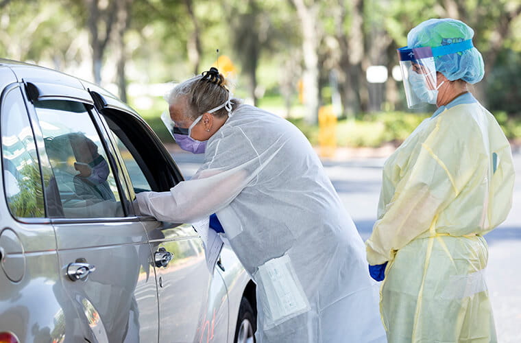 Two professionals in PPE working a covid drive through testing center