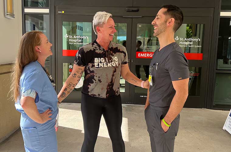A smiling Lara Warn visits with cardiologist Jason Levine, MD, and physician assistant Samantha Radigan at St. Anthony's Hospital.