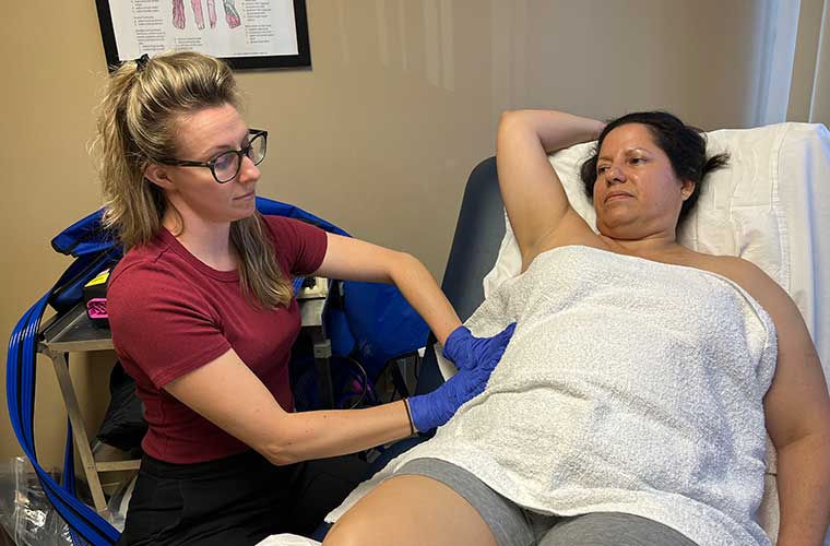 Shelby Green, a lymphedema therapist, uses a light circular touch to move lymphatic fluid near Odalmis Ricardo-Perez’s right surgical site during a treatment session.