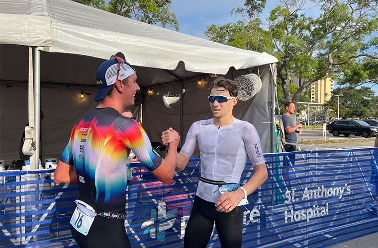 Two men dressed in athletic clothing shake hands after a race.
