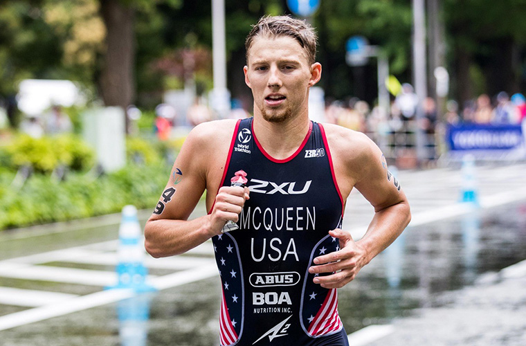 A young man in an athletic suit runs along a street during a race.