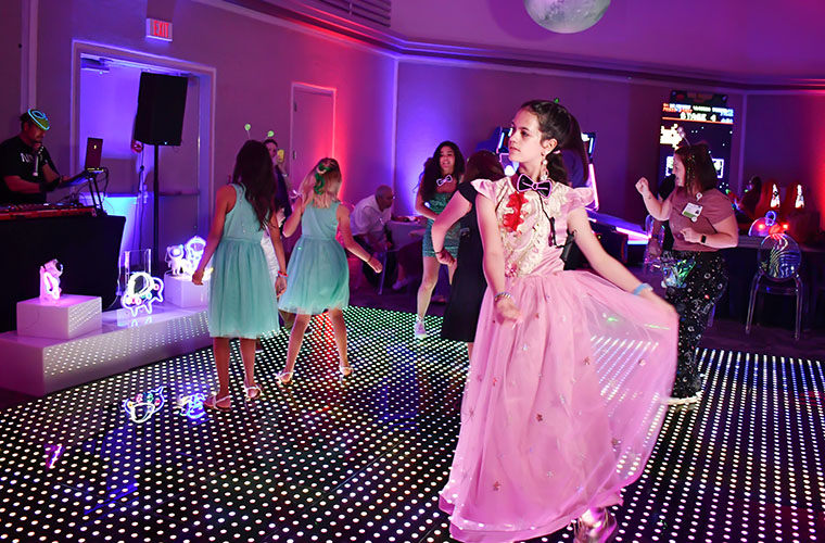 A young girl in a pink dress danced on a colorful dance floor.