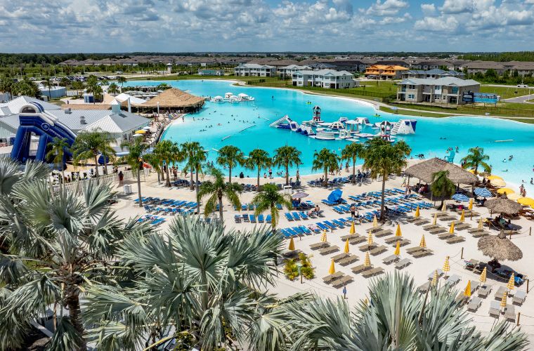 A vibrant water lagoon and community featuring colorful slides and pools filled with people enjoying the surroundings.