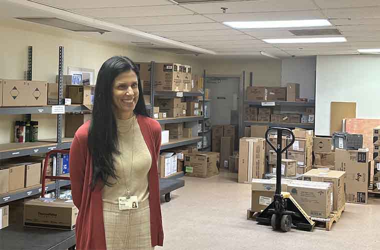 Woman with long dark hair stands in a room surrounded with boxes.
