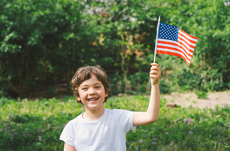 A young boy holding a small American flag and smiling