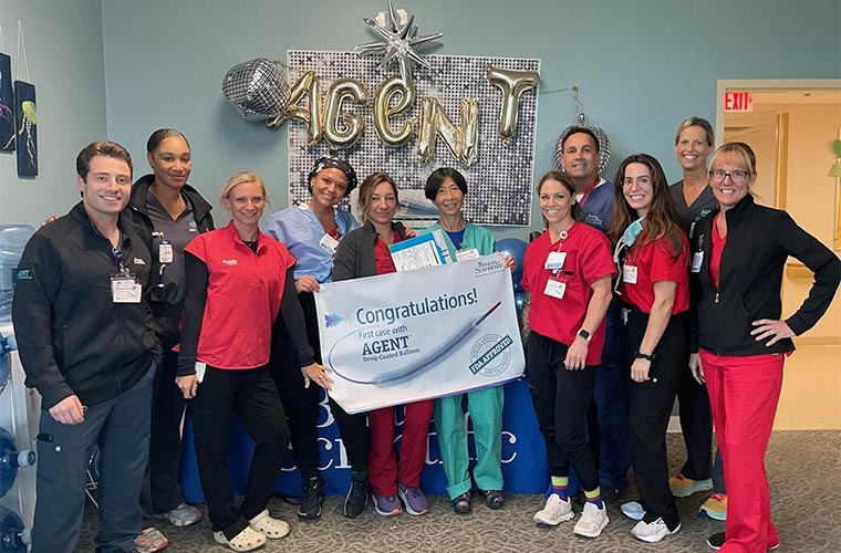 Group of people in medical scrubs holding a holding a congratulatory banner that says first case with AGENT.