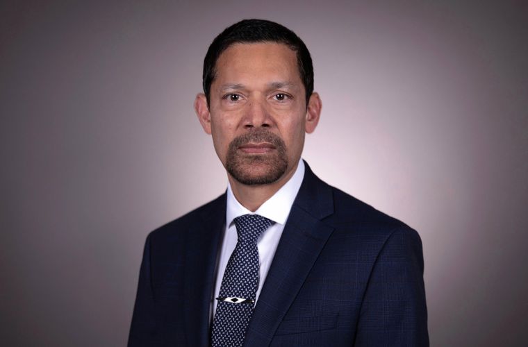 A headshot of Dr. Arif Asif. He is wearing a navy color suit jacket, a white button up shirt and a navy and a white polka dot tie with a tie clip. He has short dark hair with a goatee.